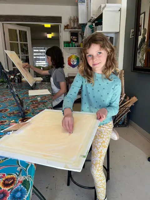 young artist smiling in studio while working on artwork