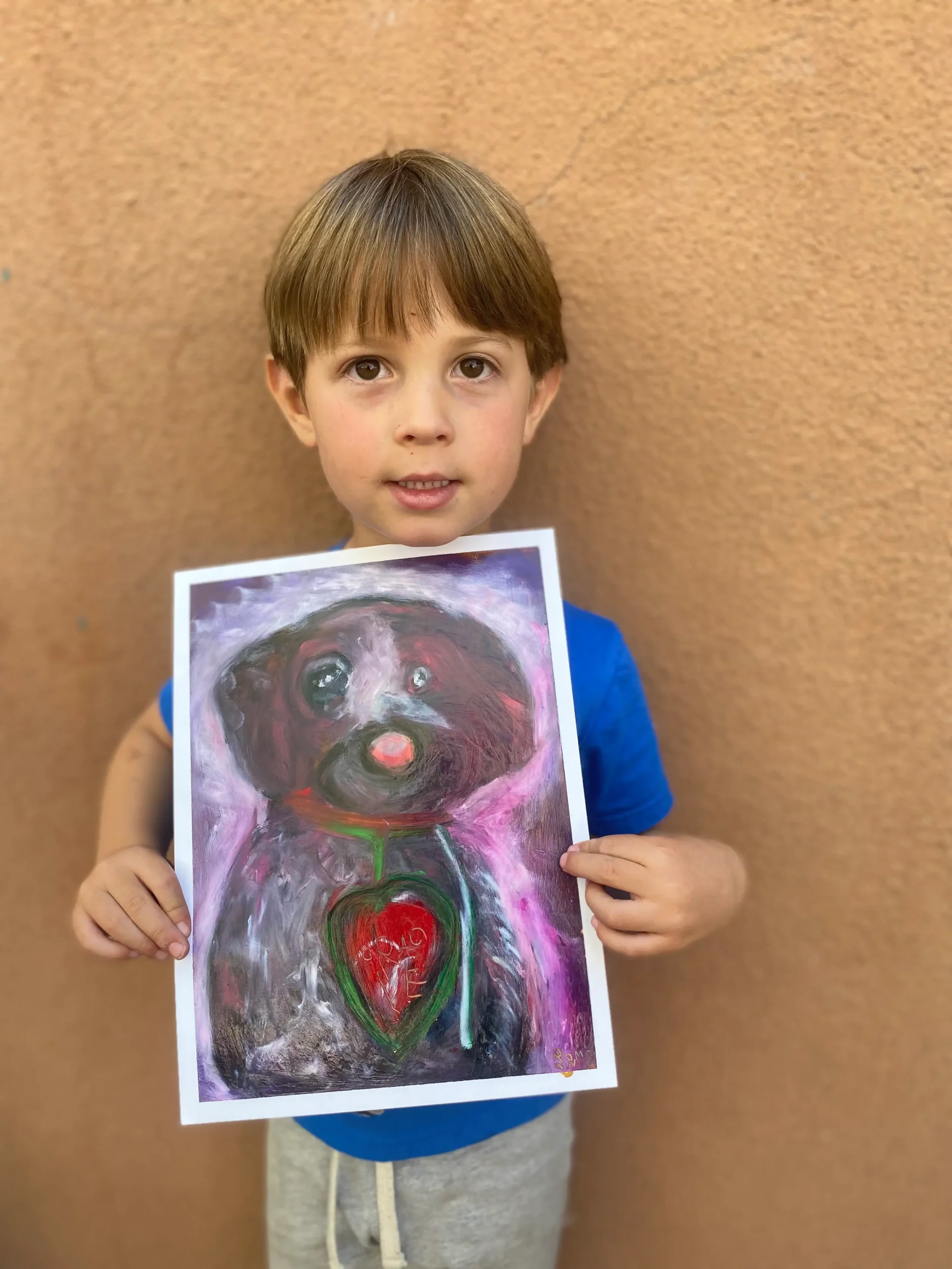 artwork from young boy holding his art of a dog