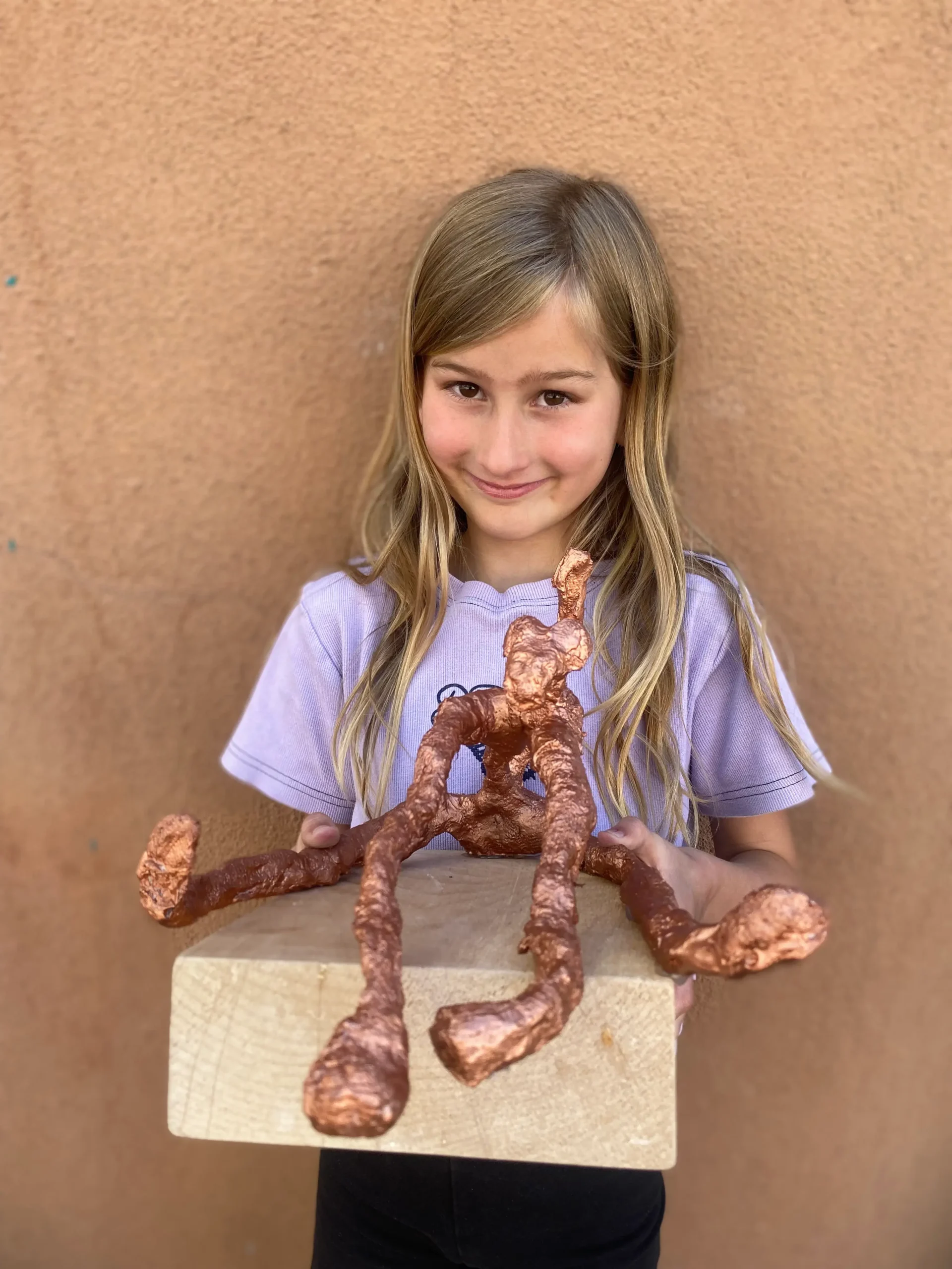 Young artist holding her sculpture of cool figure
