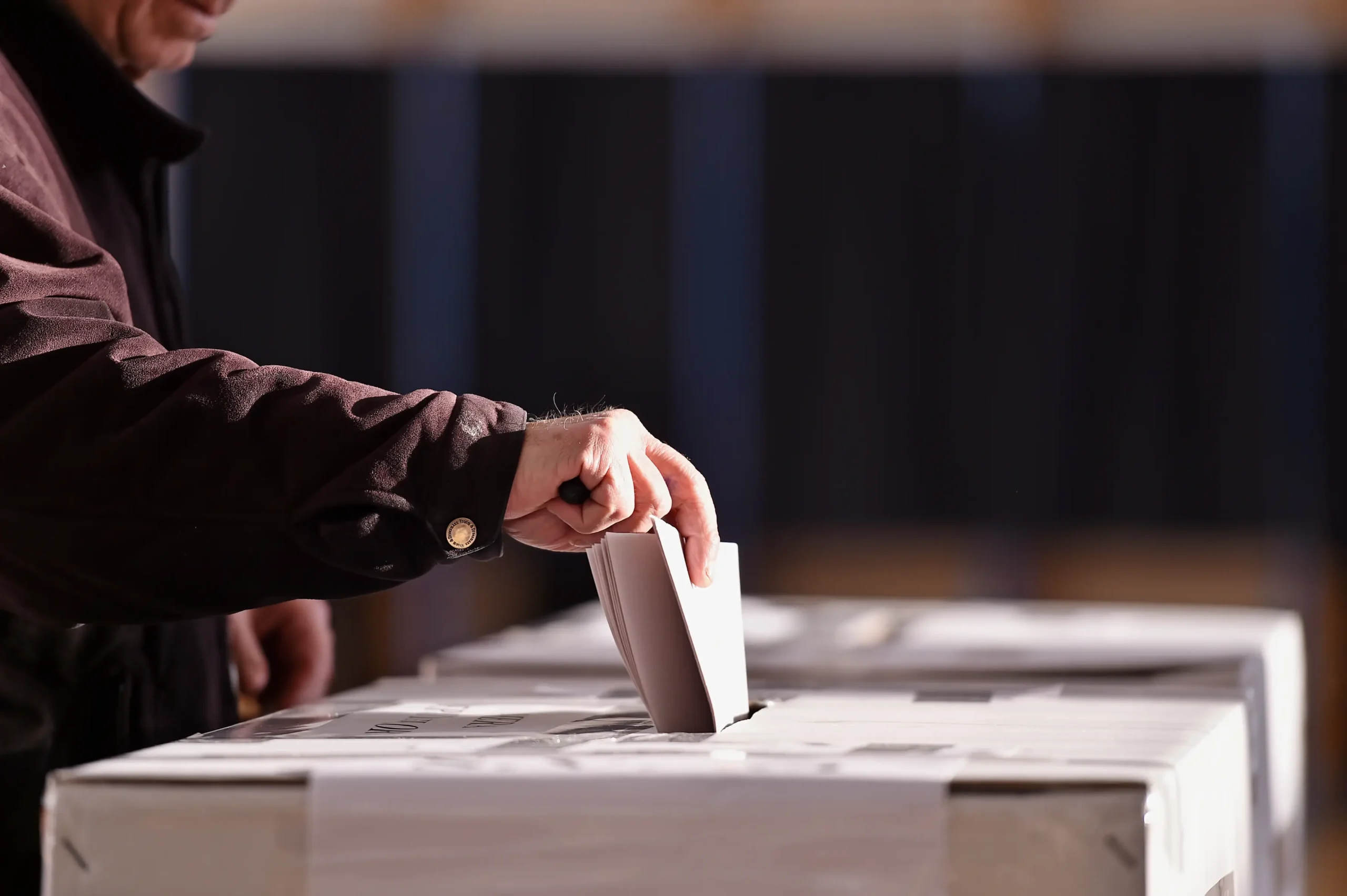 person inserting paper ballot at voting station