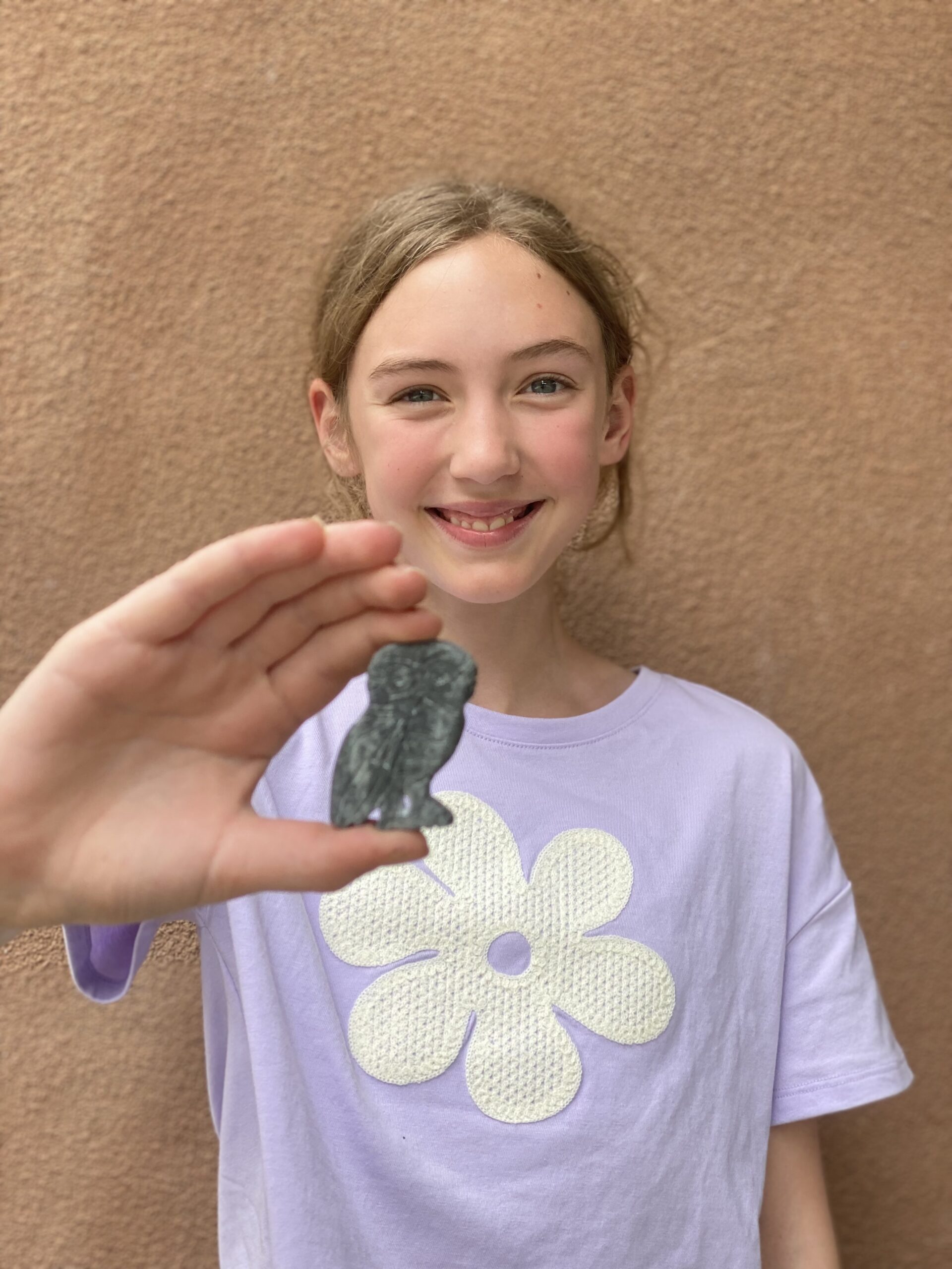 young girl holding up an owl sculpture