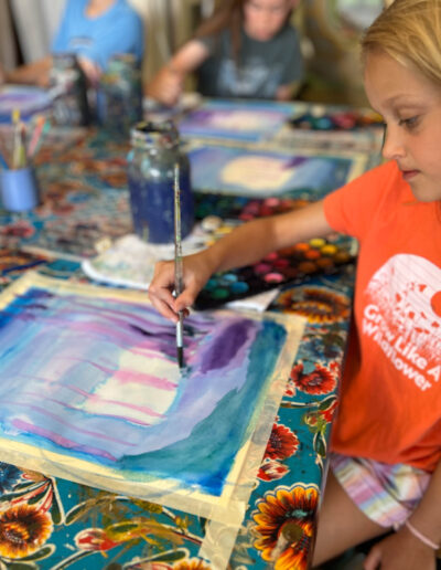 young girl paints picture in studio