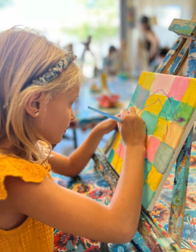 Young girl paints on background of different colored squares