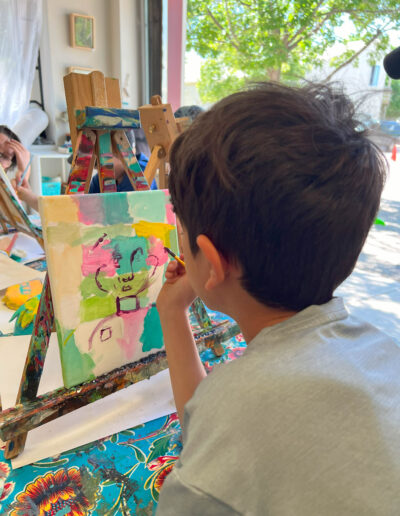 Young boy paints a face over different color squares