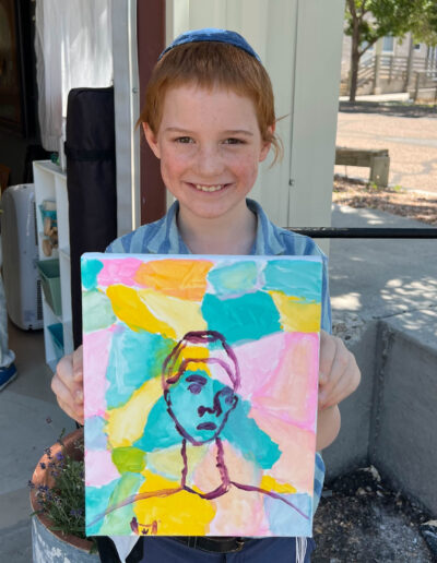 young boy displays his colorful artwork