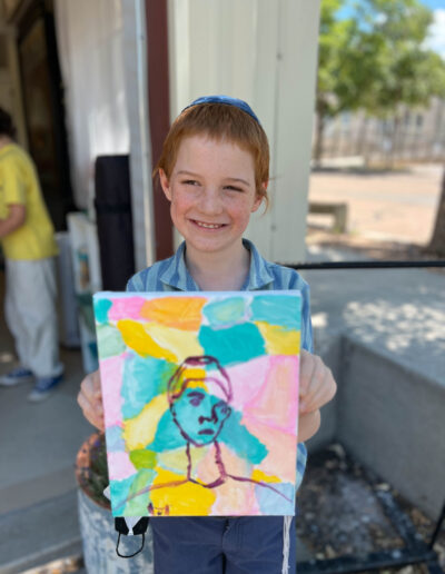 young boy displays his colorful artwork