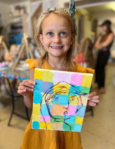 young girl displays her colorful artwork of person