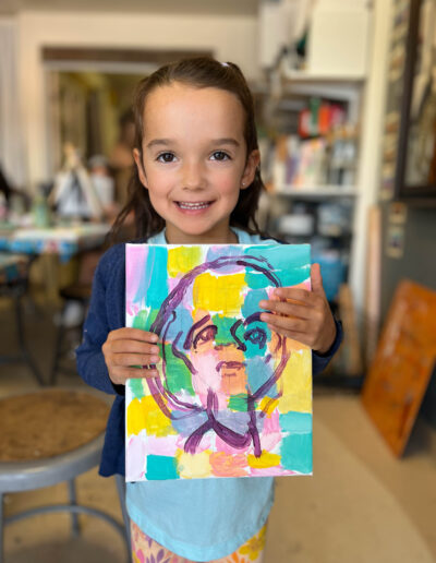 young girl shows off her colorful artwork