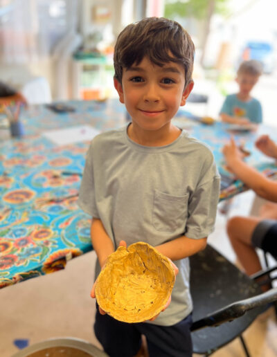 Young boy shows off his painted pottery