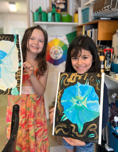 two young girls smile and share their artwork