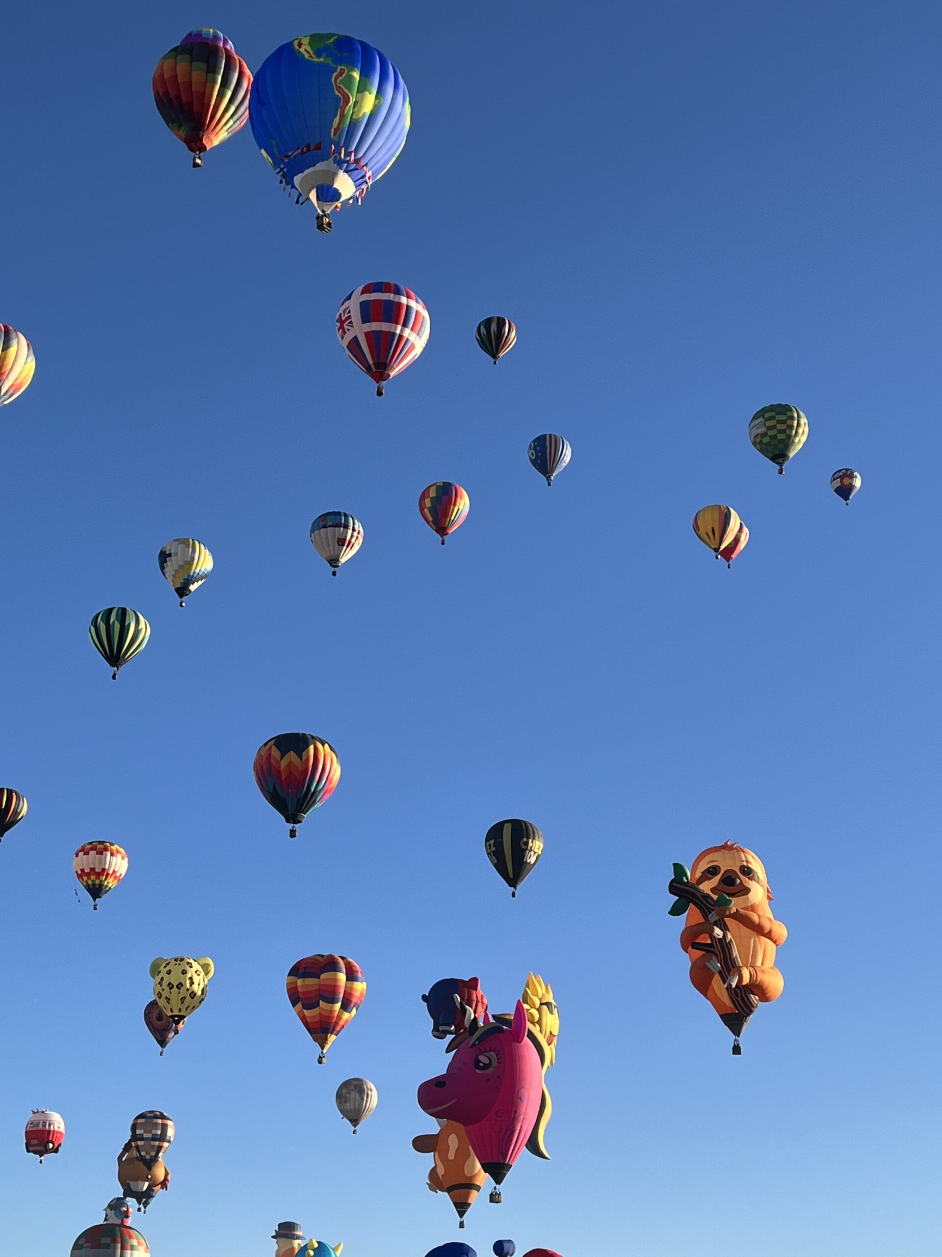 many hot air balloons against a blue sky