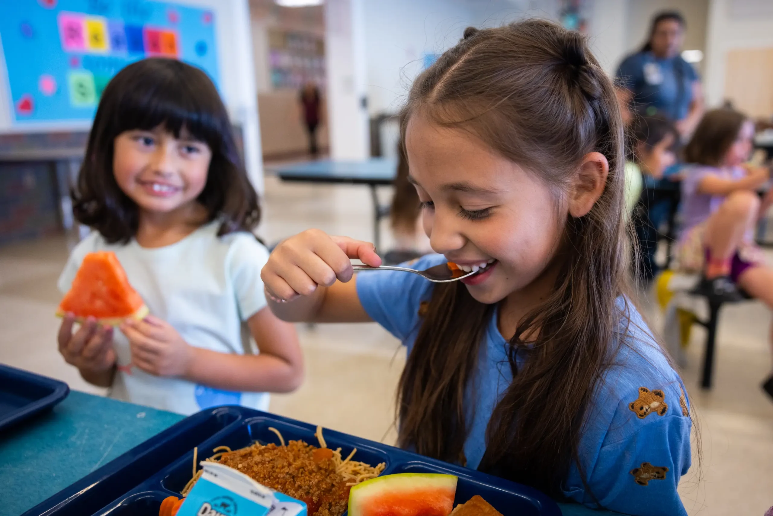 Children enjoying their scratch-made school lunch, especially the fresh watermelon.