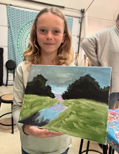 girl displaying her painting of a stream